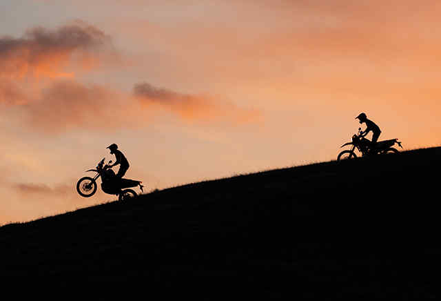 Duas motos Honda da série 300 a descer uma colina ao pôr-do-sol