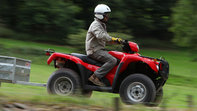 Vista lateral do Fourtrax 250, conduzida por um modelo, cenário de campo.