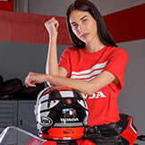 Senhora com um Top Honda vermelho apoiada num capacete de moto Honda.