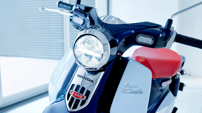 Honda Super Cub estacionada num cenário moderno.