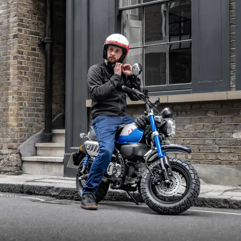 Honda Monkey 125 com condutor estacionada na berma da estrada