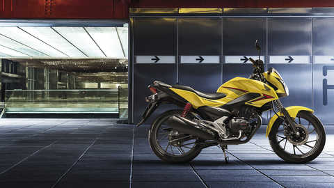 Vista lateral da CB125F em amarelo Pearl Twinkle estacionada, virada para a direita (localiza&ccedil;&atilde;o urbana)