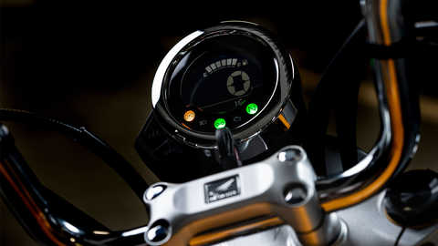 Monkey 125 cc, vista frontal lateral esquerda a 3 quartos, homem ao telefone apoiado na moto