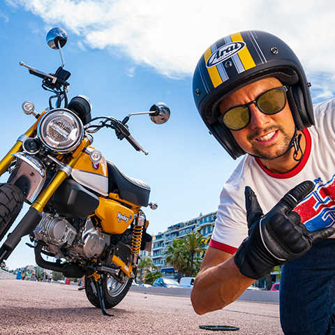 Monkey 125 cc, vista frontal lateral esquerda a 3 quartos, homem com capacete em segundo plano