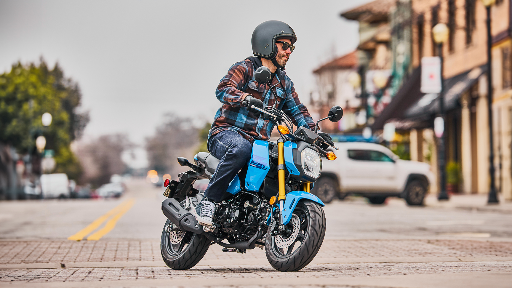 MSX125 Grom em azul na estrada com piloto a fazer uma curva 