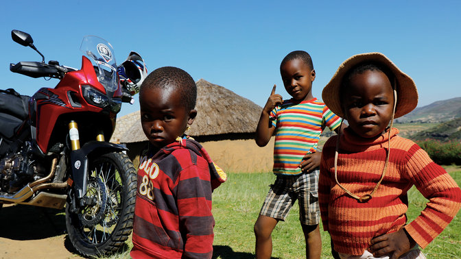 Crianças pequenas ao ar livre à volta de uma Africa Twin CRF1000L