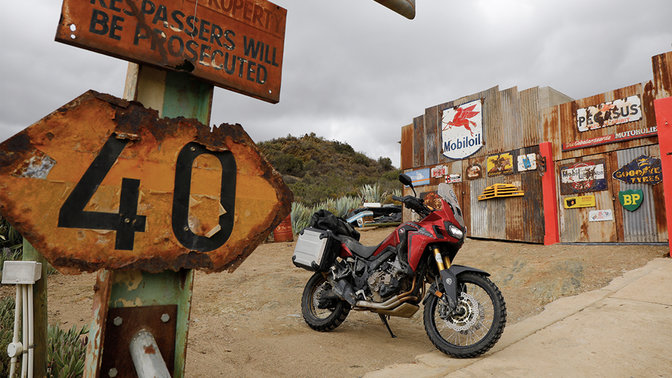 Honda CRF1000L Africa Twin estacionada numa estação de serviço ao lado da estrada.