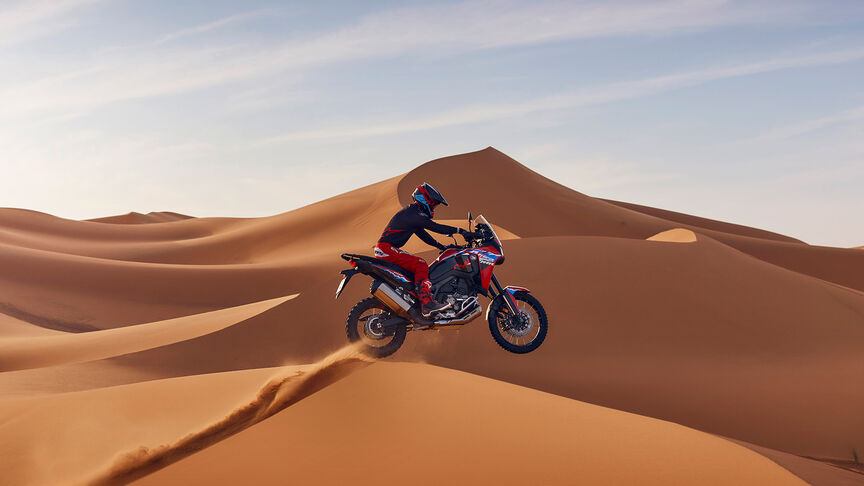 Africa Twin fora de estrada com condutor numa duna de areia