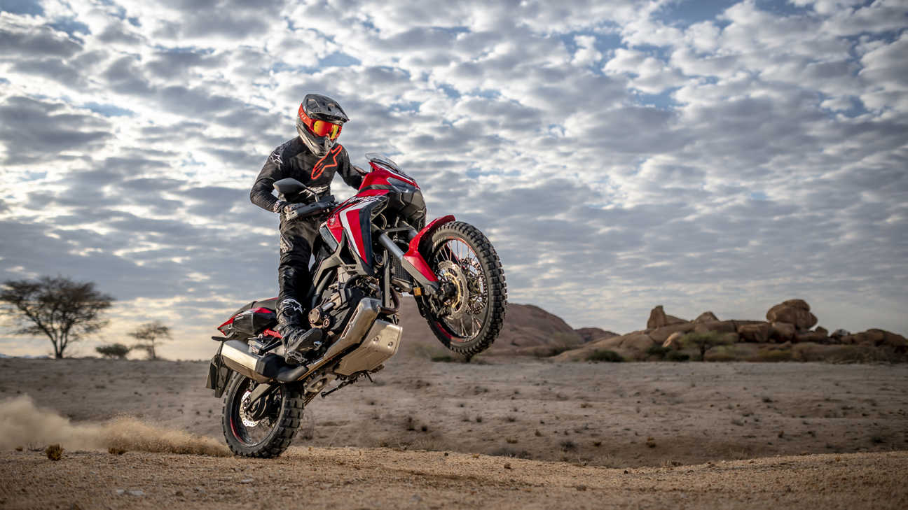 Honda Africa Twin, vista a 3 quartos da frente lateral direita, a fazer cavalinho numa paisagem desértica