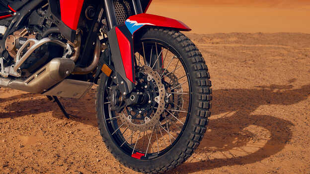 Grande plano das rodas de uma moto CRF1100L Africa Twin num cenário de deserto.