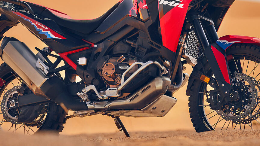 Modelo a conduzir uma mota CRF1100L Africa Twin num cenário de deserto.