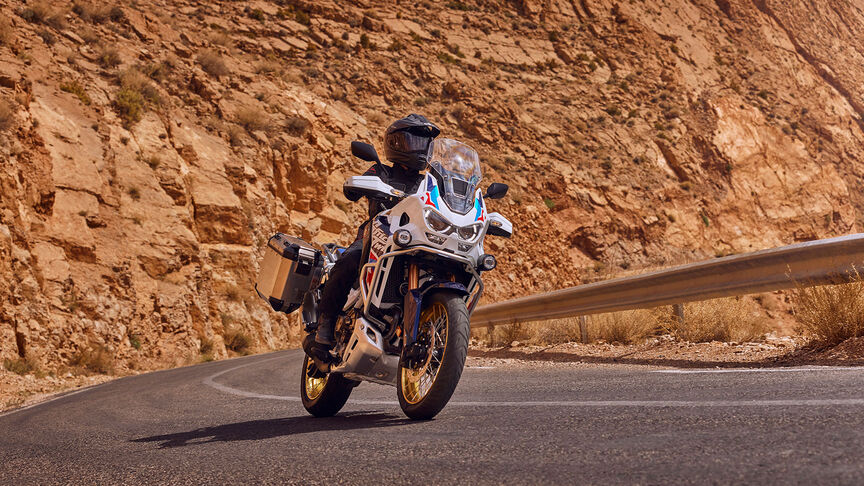 Vista frontal da Honda CRF1100 Africa Twin Adventure Sports a 3/4 num cenário montanhoso.