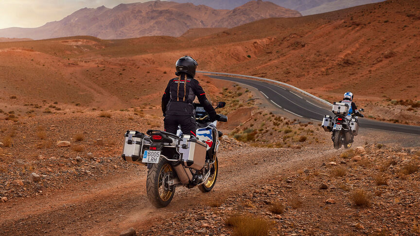 Vista frontal da Honda CRF1100 Africa Twin Adventure Sports a 3/4 num cenário montanhoso.