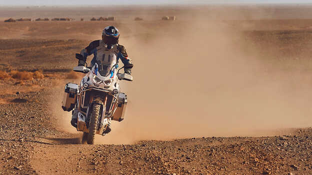 condutor virado para a frente na Honda CRF1100 Africa Twin Adventure Sports num cenário de deserto.