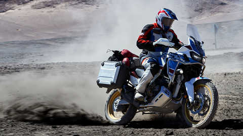 Condutor numa moto Honda Africa Twin Adventure Sports a deslizar fora-de-estrada.