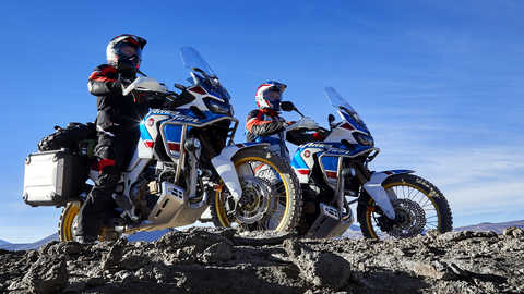 Dois condutores em motos Honda Africa Twin Adventure Sports a olhar para um desfiladeiro c&eacute;nico.