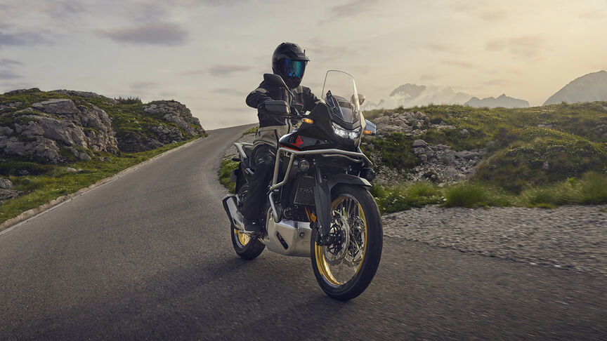 Modelo a conduzir uma moto XL750 Transalp num cenário florestal.