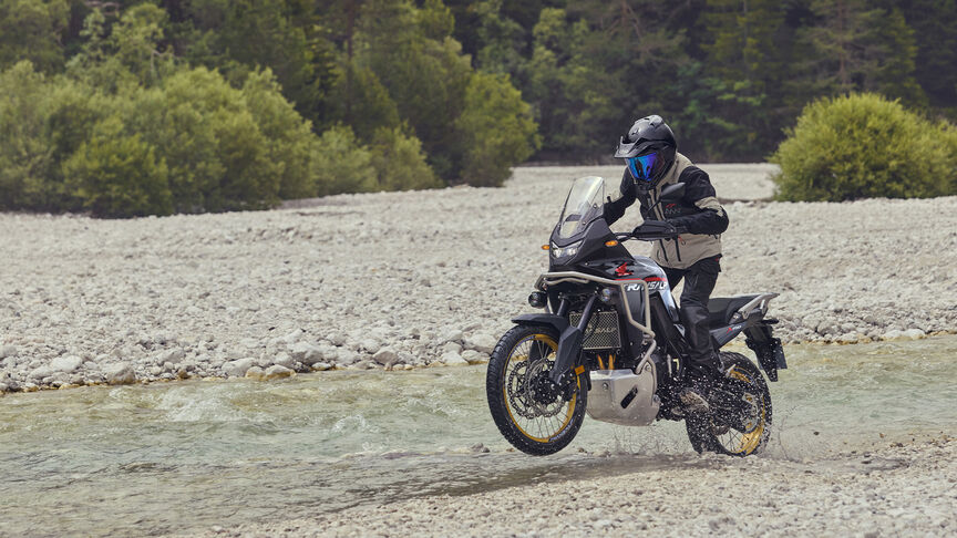 Modelo a conduzir uma moto XL750 Transalp num cenário florestal.