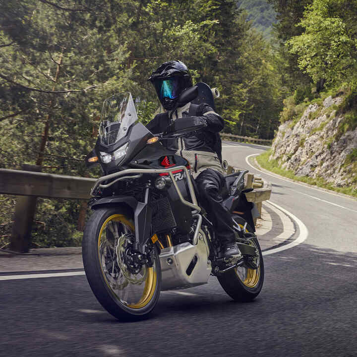 Modelo a conduzir a moto XL750 Transalp num cenário montanhoso.