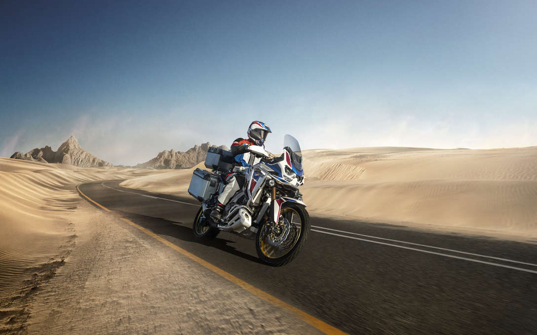 Honda Africa Twin Adventure Sports, vista a 3 quartos da frente lateral direita, conduzida numa estrada numa paisagem desértica