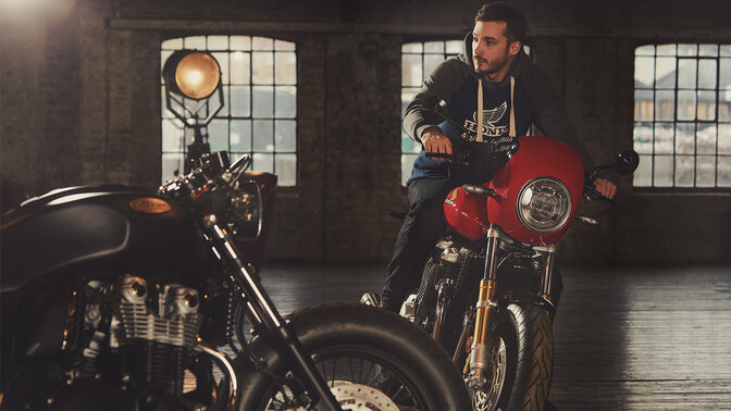 Modelo de roupa Honda Vintage com camisola com capuz a bordo de uma moto