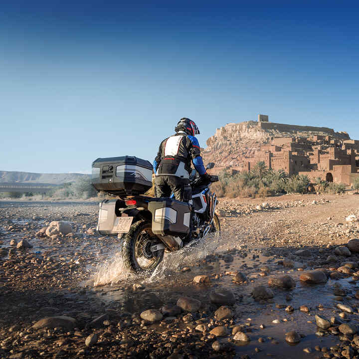 Condutor a bordo de uma CRF1100 ATAS voltada para trás com acessórios de turismo.
