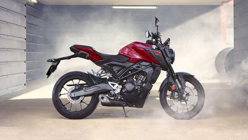 Modelo a conduzir uma moto num cenário urbano.