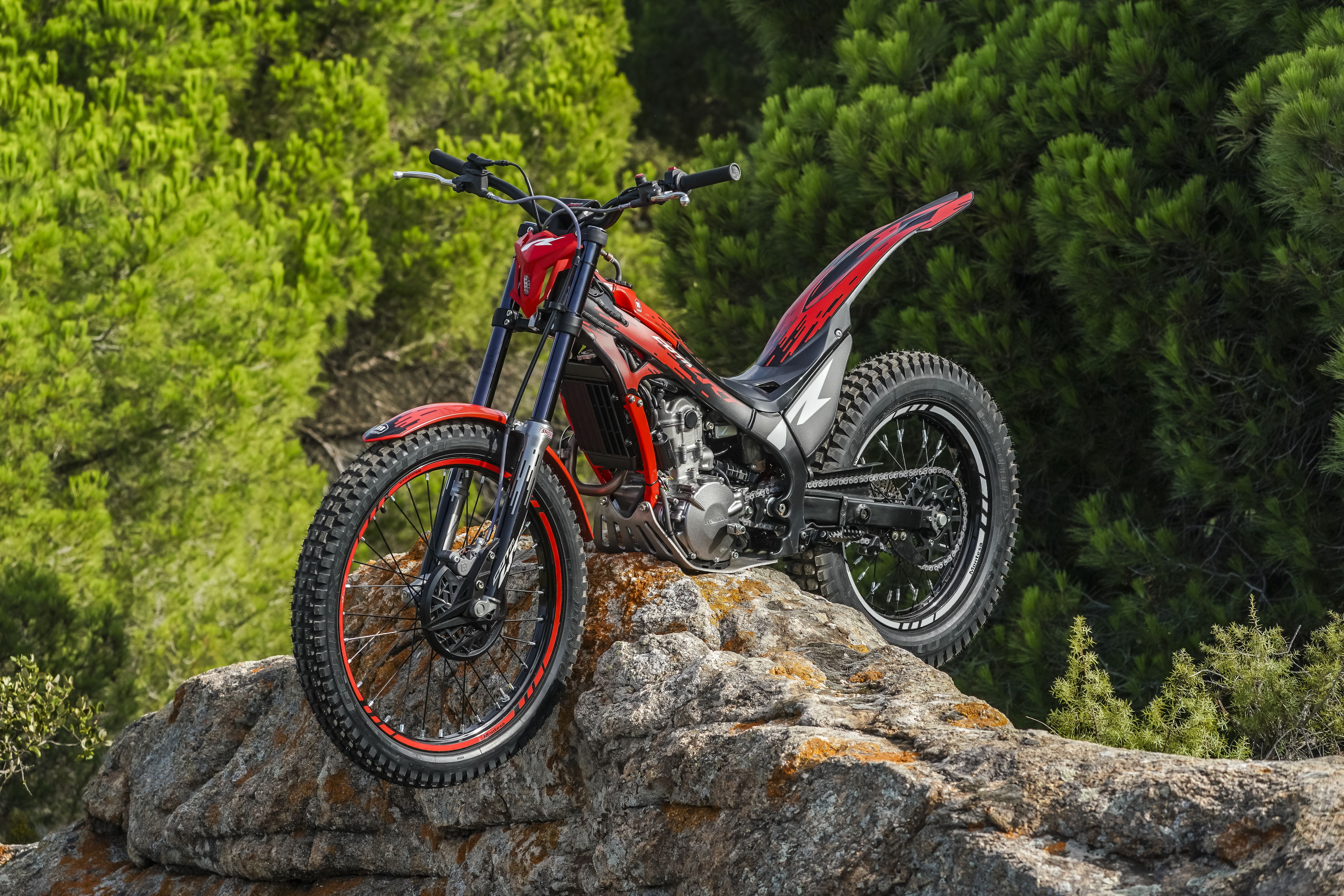 Moto de trial Montesa Cota 260R sobre uma saliência rochosa num ambiente florestal.