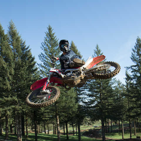 CRF450R a saltar, com condutor. Estrada de terra batida.