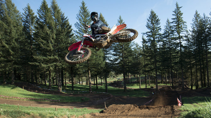 CRF450R a saltar, com condutor. Local com pista de terra.