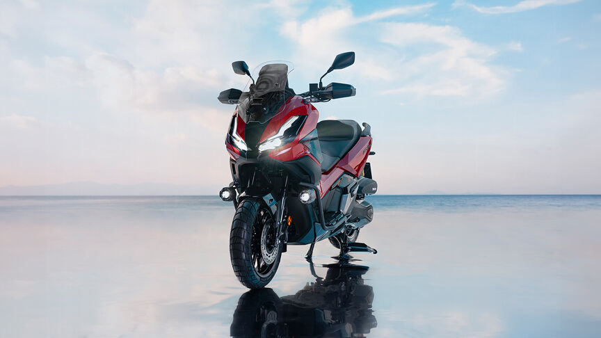Vista frontal a 3/4 da Honda ADV350 num cenário costeiro.