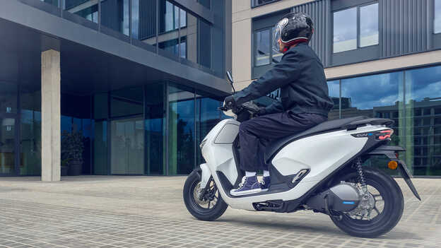 Modelo a conduzir uma moto Honda CUV e a demonstrar o fácil assistente de marcha-atrás.