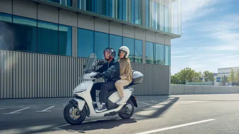 Modelos a conduzir a moto Honda CUV e num cenário urbano.