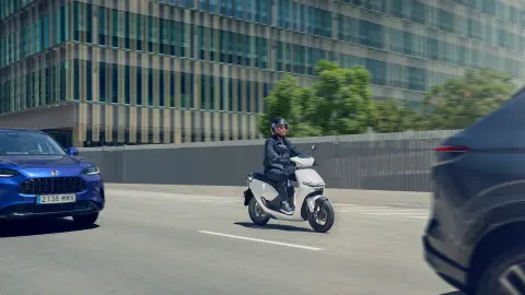 Piloto a conduzir uma moto Honda CUV e num cenário urbano.