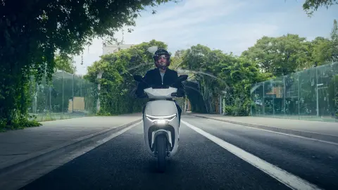 Vista frontal de um modelo a conduzir uma moto Honda CUV e num cenário urbano.