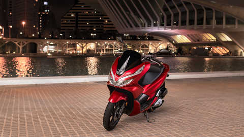 Vista dianteira de tr&ecirc;s quartos da Honda PCX125 numa localiza&ccedil;&atilde;o urbana.