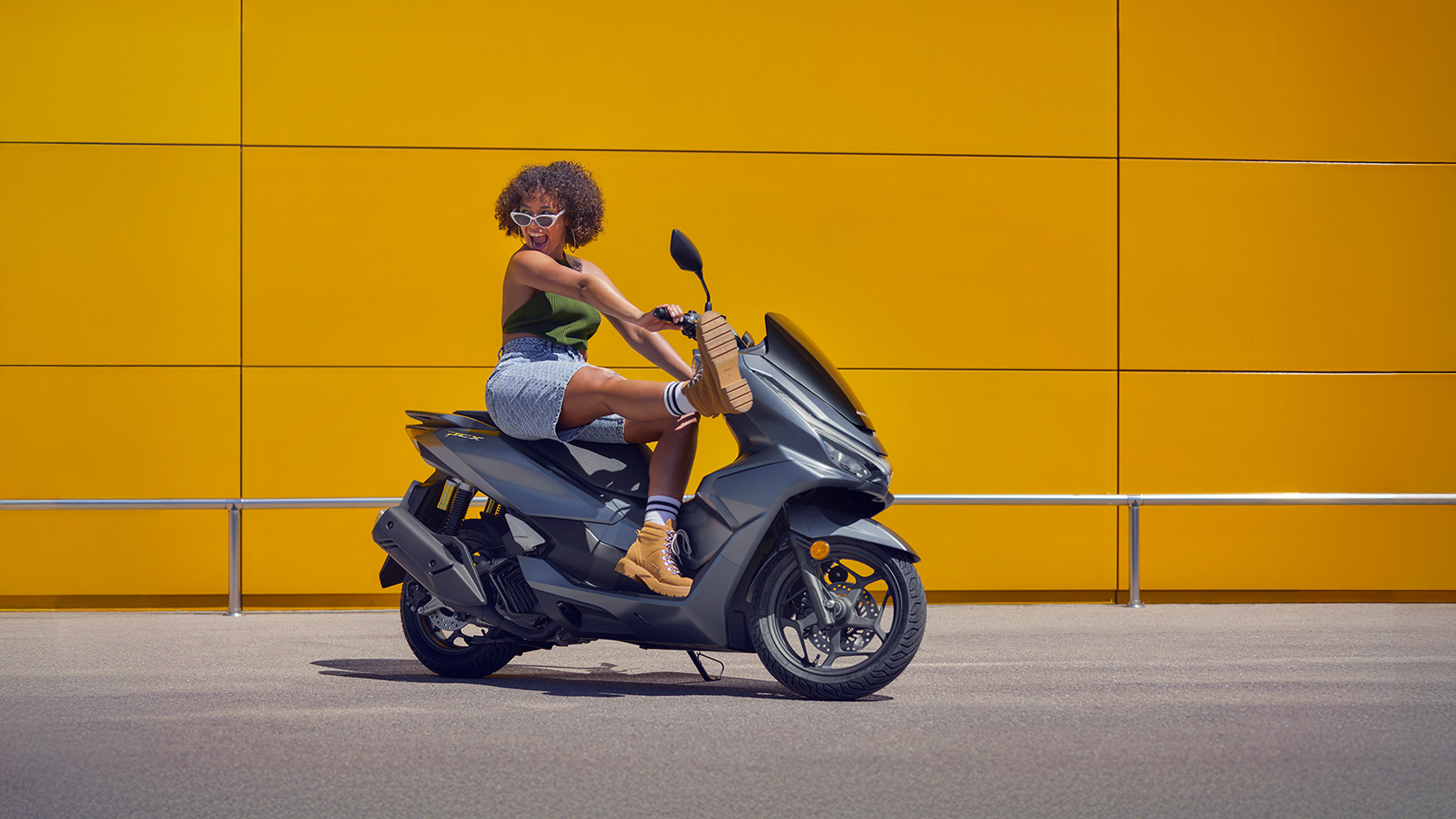 Modelo sentado na mota PCX 125.