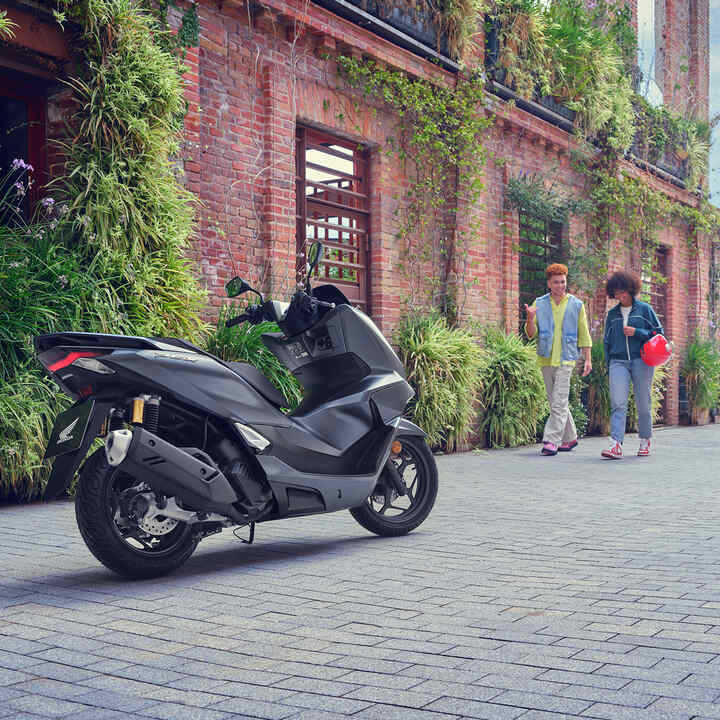 Modelos a caminhar na direção da moto PCX125.