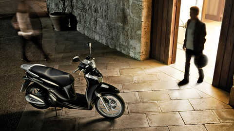 Moto preta da SH Mode com condutor masculino a entrar no plano.