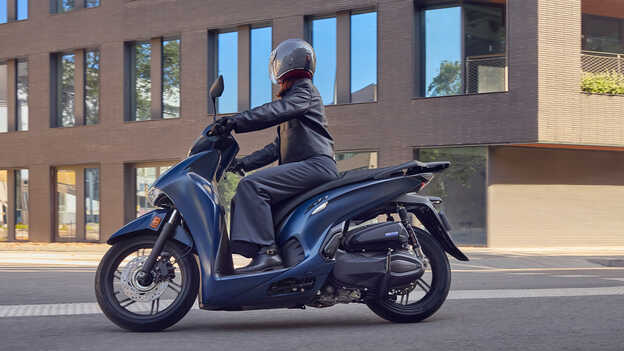 Condutor numa Honda SH350 vista de lado num cenário urbano.
