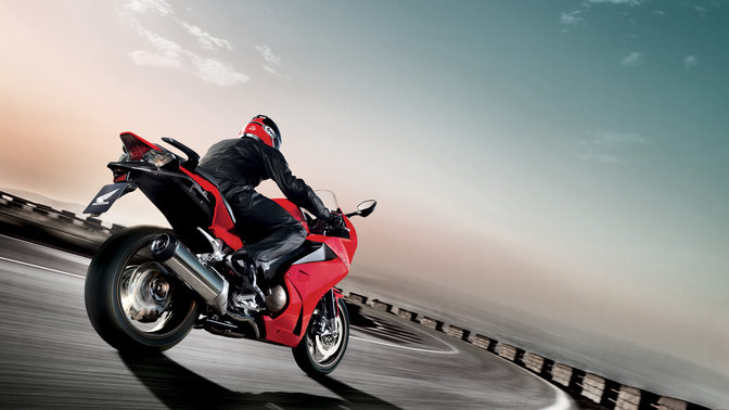 Perspetiva dianteira a três quartos da scooter Honda SH Mode preta com condutor. Virada para a direita (em estrada).
