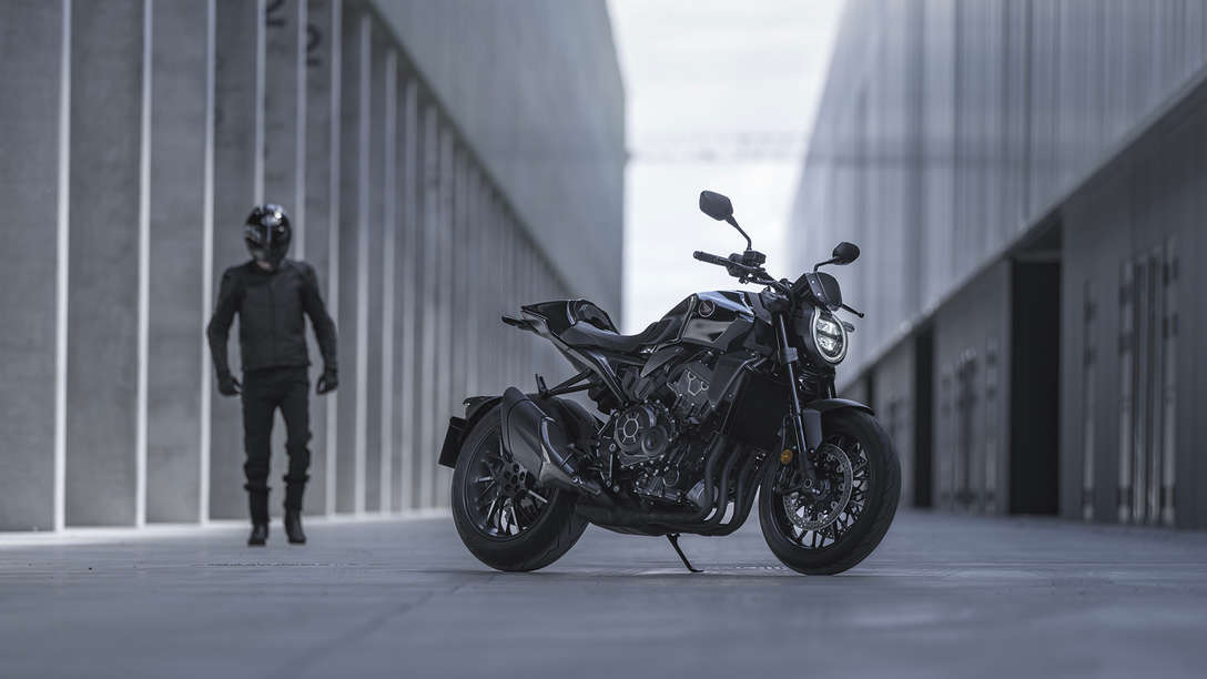 Honda CB1000R Black Edition - homem de pé ao lado da moto na rua entre edifícios