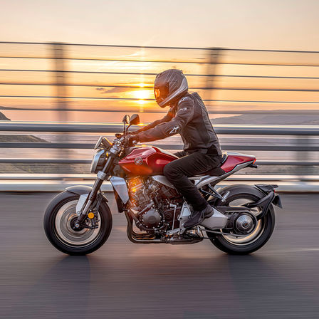 Honda CB1000R, lado esquerdo, com o condutor, na estrada, com o nascer do sol