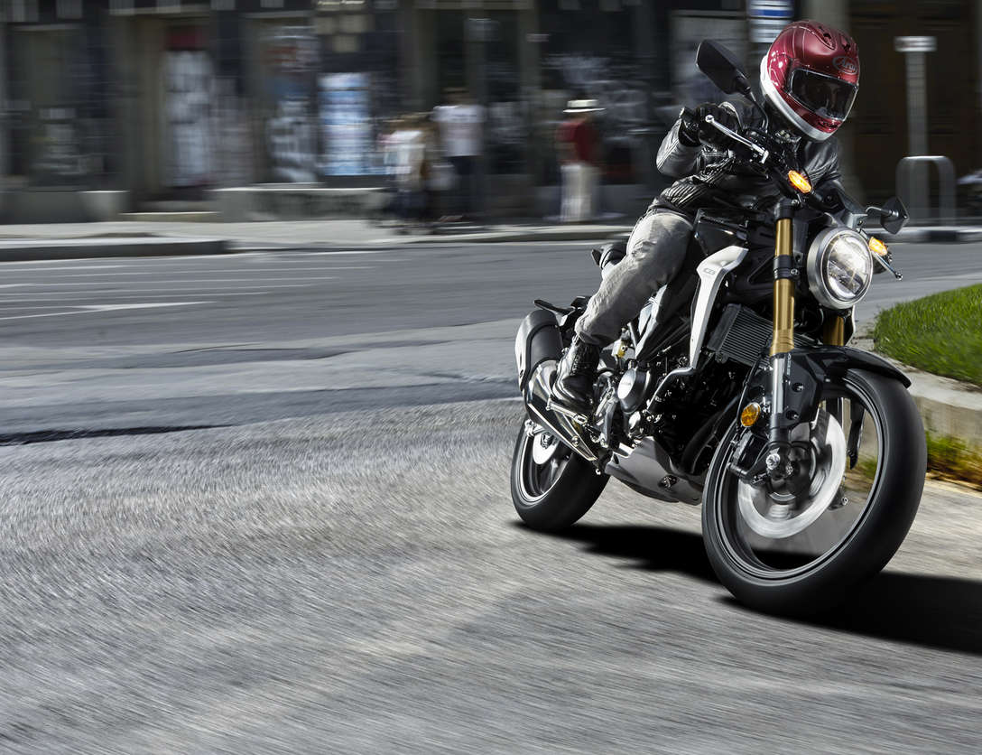 Vista dianteira a três quartos da Honda CB300R Sports Café, a ser conduzida na rua.