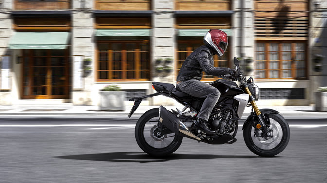 Vista lateral de uma imagem de ação da Honda CB300R Neo Sports Café a ser conduzida em estrada.