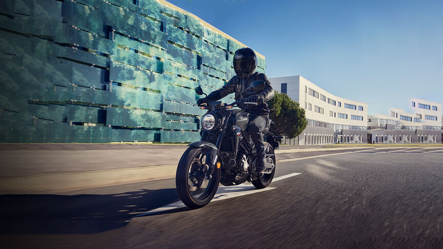 Vista dianteira a três quartos da Honda CB300R observada por uma mulher num estúdio.