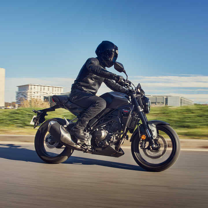 Vista lateral da Honda CB300R a ser conduzida em estrada.