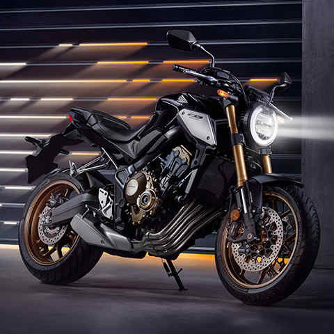 CB650R Neo Sports Café, vista frontal lateral direita a 3 quartos, numa zona urbana à noite