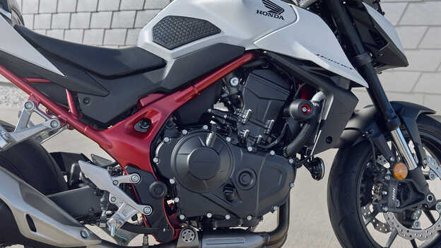 Honda CB750 Hornet com homem encostado a um prédio.
