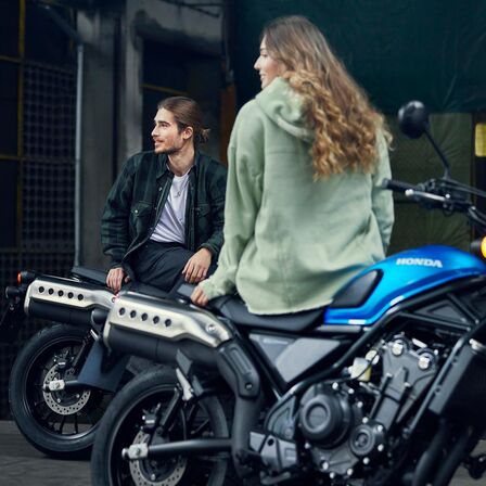 Honda CL500 com modelos sentados na moto.